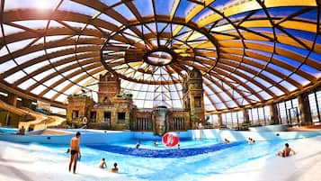 Swimmers can enjoy the spacious pool area with multiple lanes, surrounded by ornate stone structures and a waterfall feature.
