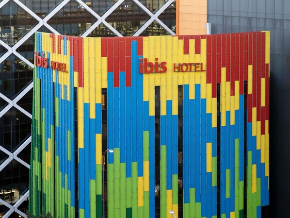 Fachada colorida de un hotel con franjas verticales y el nombre 'Tobis Hotel' a la vista.
