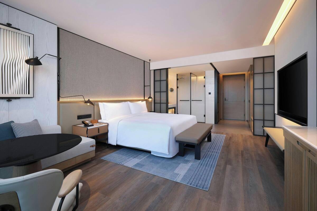 Quarto de hotel moderno com cama grande, mesas de cabeceira, escrivaninha, TV de tela plana e closet espaçoso.