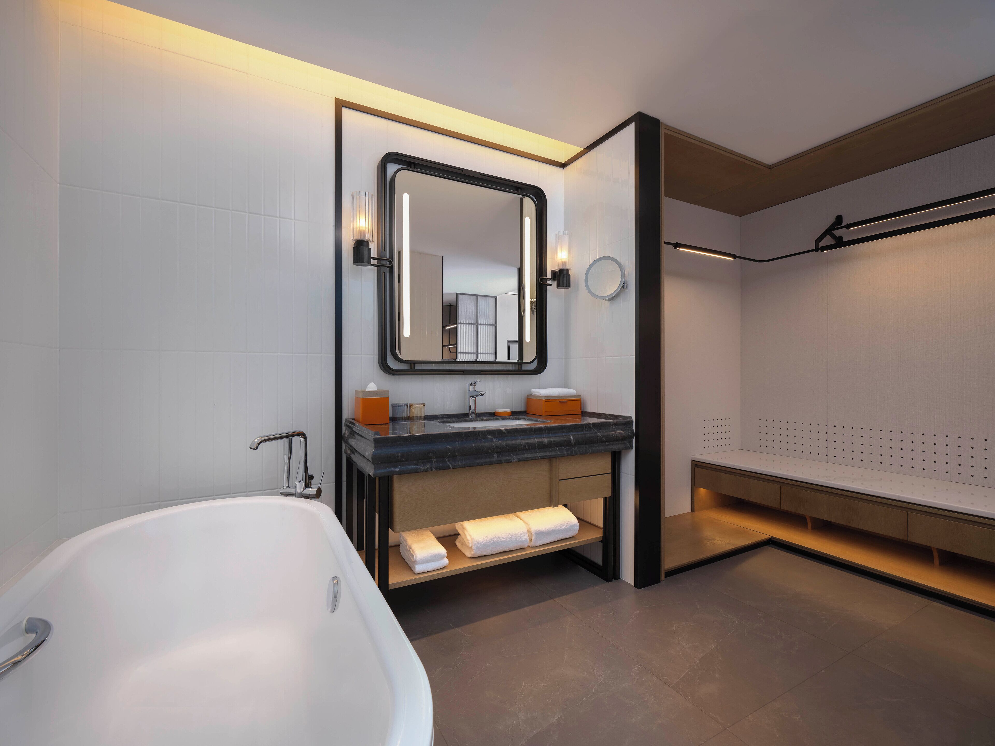 Un baño moderno con una bañera independiente, un tocador con espejo y un perchero para toallas.