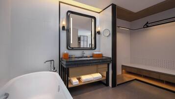 Un baño moderno con una bañera independiente, un tocador con espejo y un perchero para toallas.