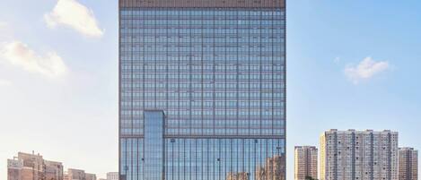 A modern Sheraton hotel with a glass facade, surrounded by high-rise buildings.