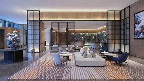 A modern lobby with a seating area, a reception desk, and a large window.