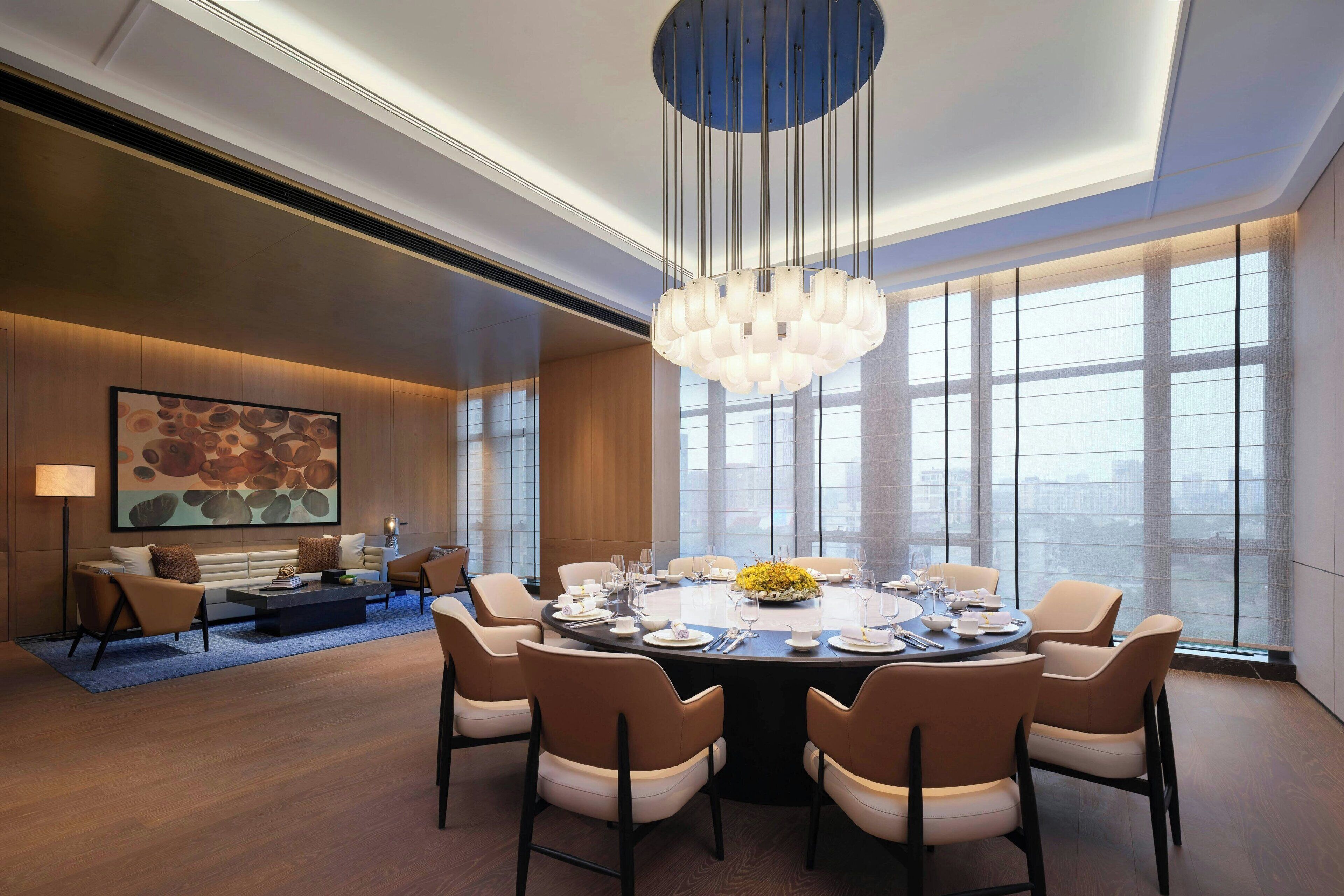 A modern dining area with a round table set for six, surrounded by six chairs.