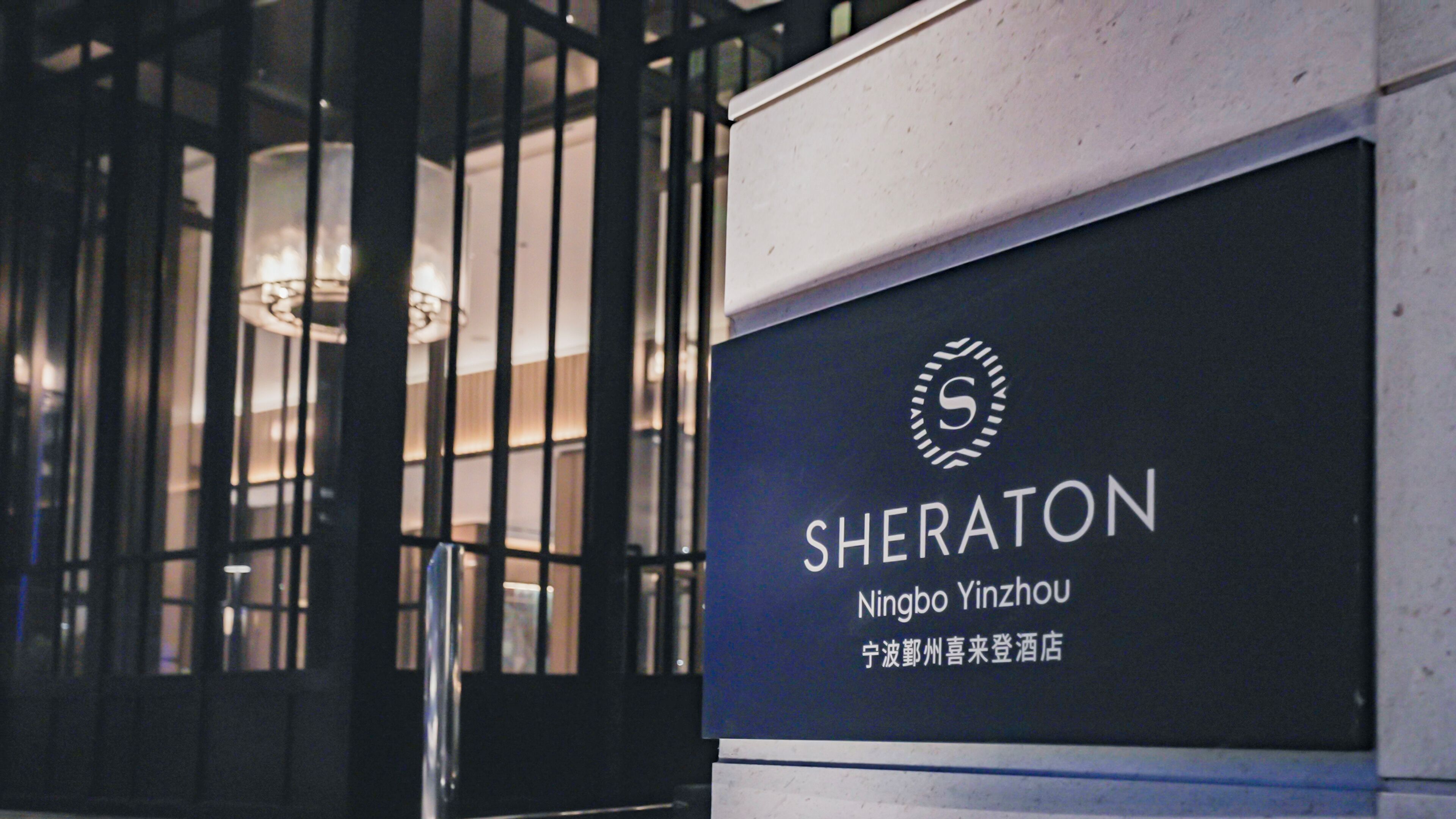 A hotel sign with the name 'SHERATON Ningbo Yinzhou' and a logo.