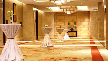 A hotel lobby with a marble floor, a reception desk, and three round tables with white tablecloths.
