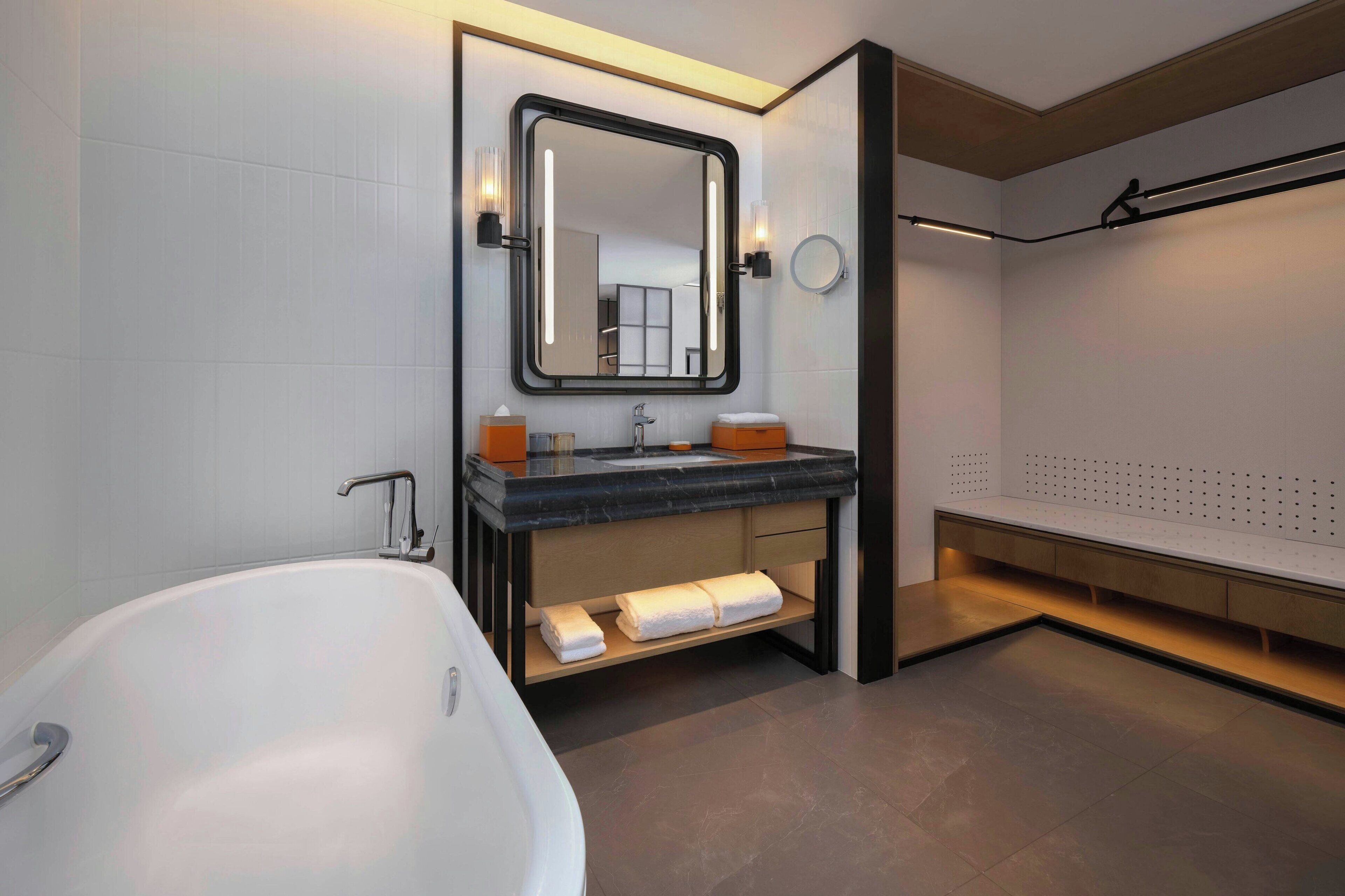 Un baño moderno con una bañera independiente, un tocador con espejo y un perchero para toallas.