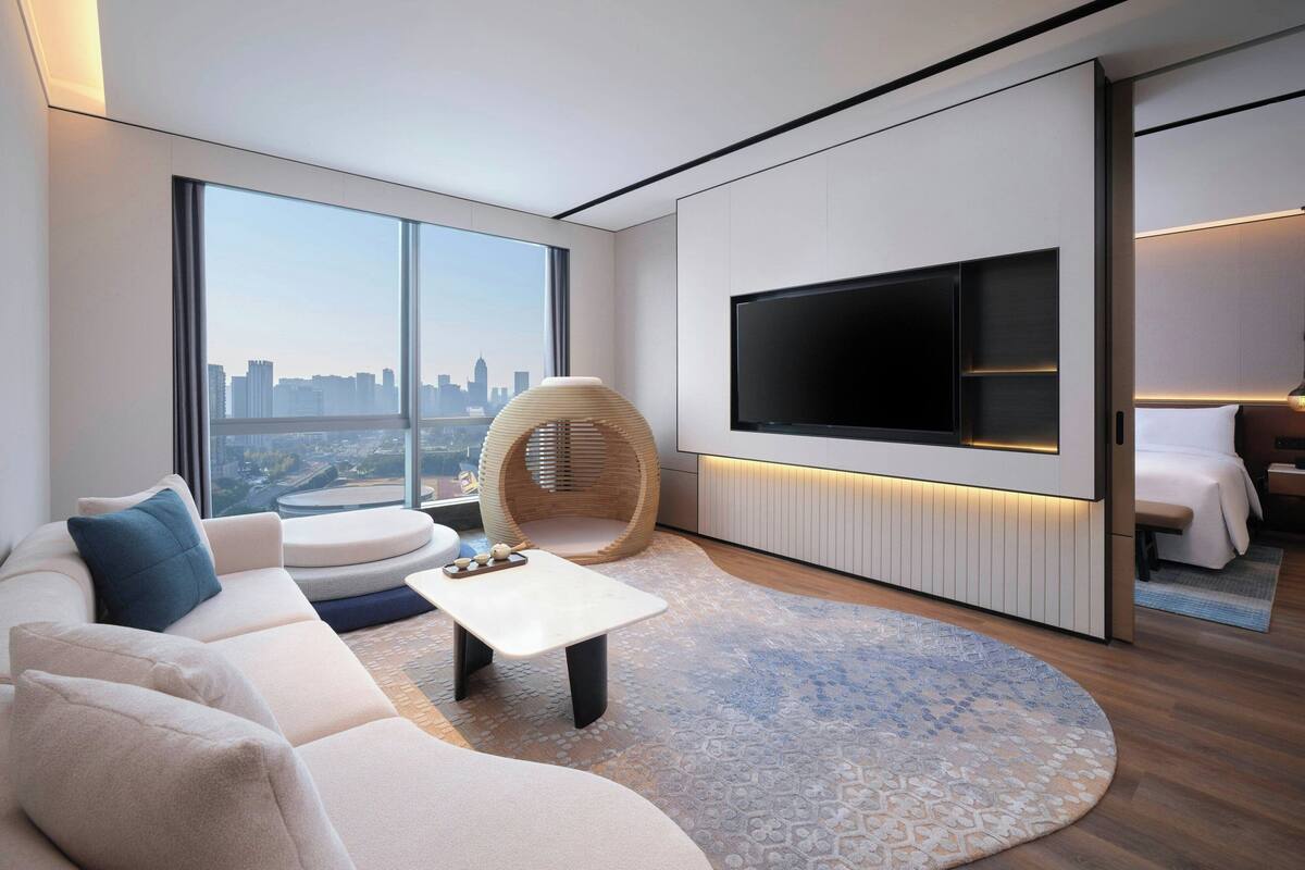 Uma sala de estar moderna com uma televisão grande, assentos confortáveis e vista para o horizonte da cidade.