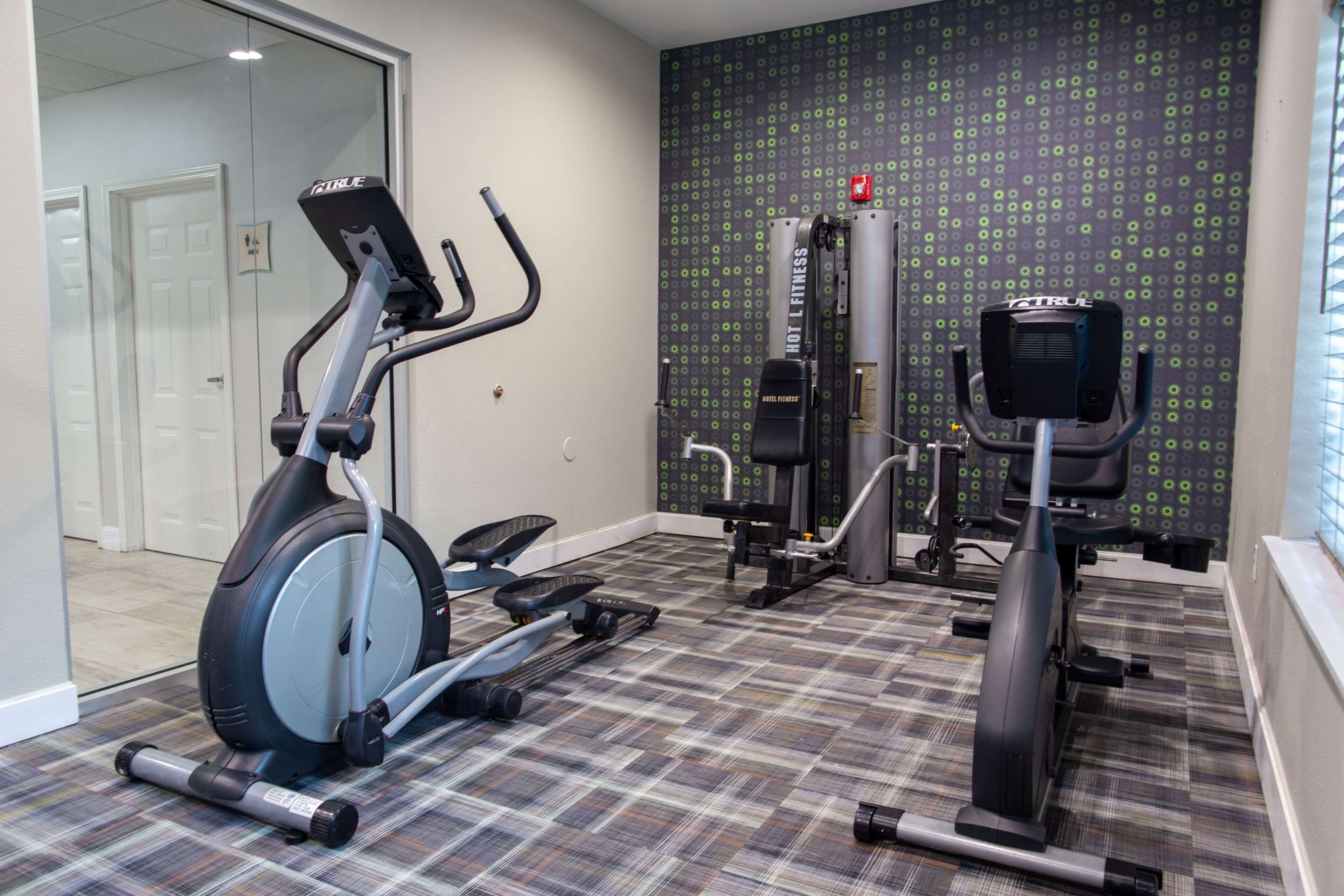 A home gym with an elliptical, a stationary bike, and a weight machine.