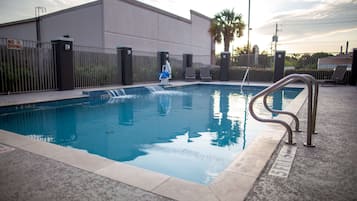 A swimming pool with a metal ladder, a 'No Diving' sign, and a palm tree in the background.