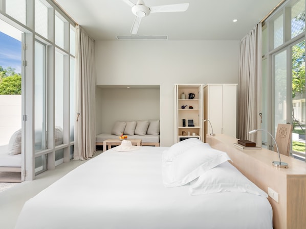 A modern hotel room with a large bed, a seating area with a table, and a wardrobe. - SALA Phuket Mai Khao Beach Resort (Mai Khao)