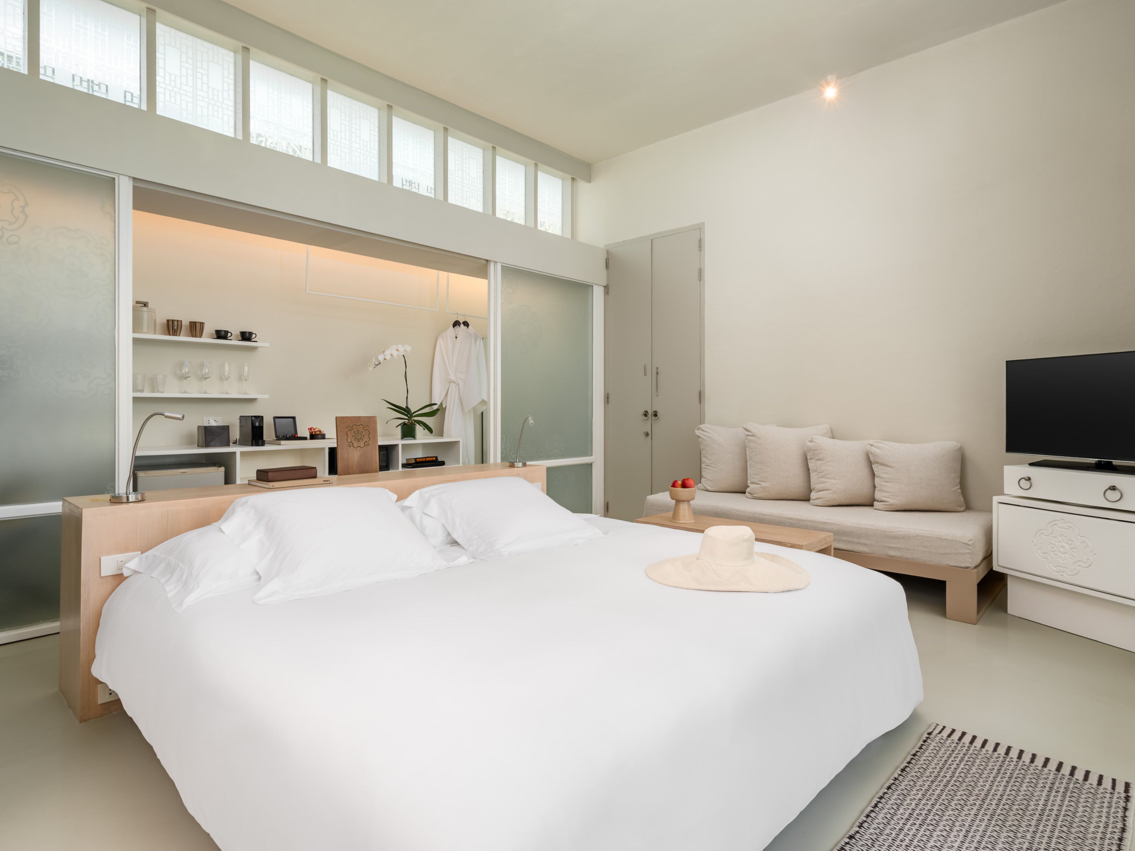 Un dormitorio moderno con una cama grande, un televisor, un sofá y un vestidor.