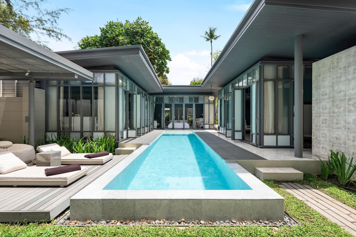 Ein moderner Poolbereich mit Liegestühlen und einem klaren, blauen Pool, umgeben von Glaswänden und einer Betonplattform.