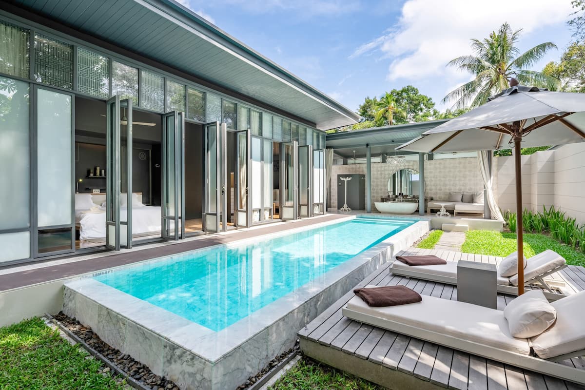 Ein modernes Haus mit Pool, Sitzgelegenheiten im Freien und einer überdachten Terrasse.