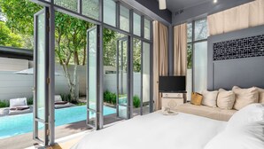 A bedroom with a large bed, a TV, and a view of a swimming pool. - SALA Phuket Mai Khao Beach Resort (Mai Khao)