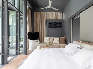 Ein modernes Hotelzimmer mit Bett, einer Couch, einem Fernseher und einem großen Fenster.