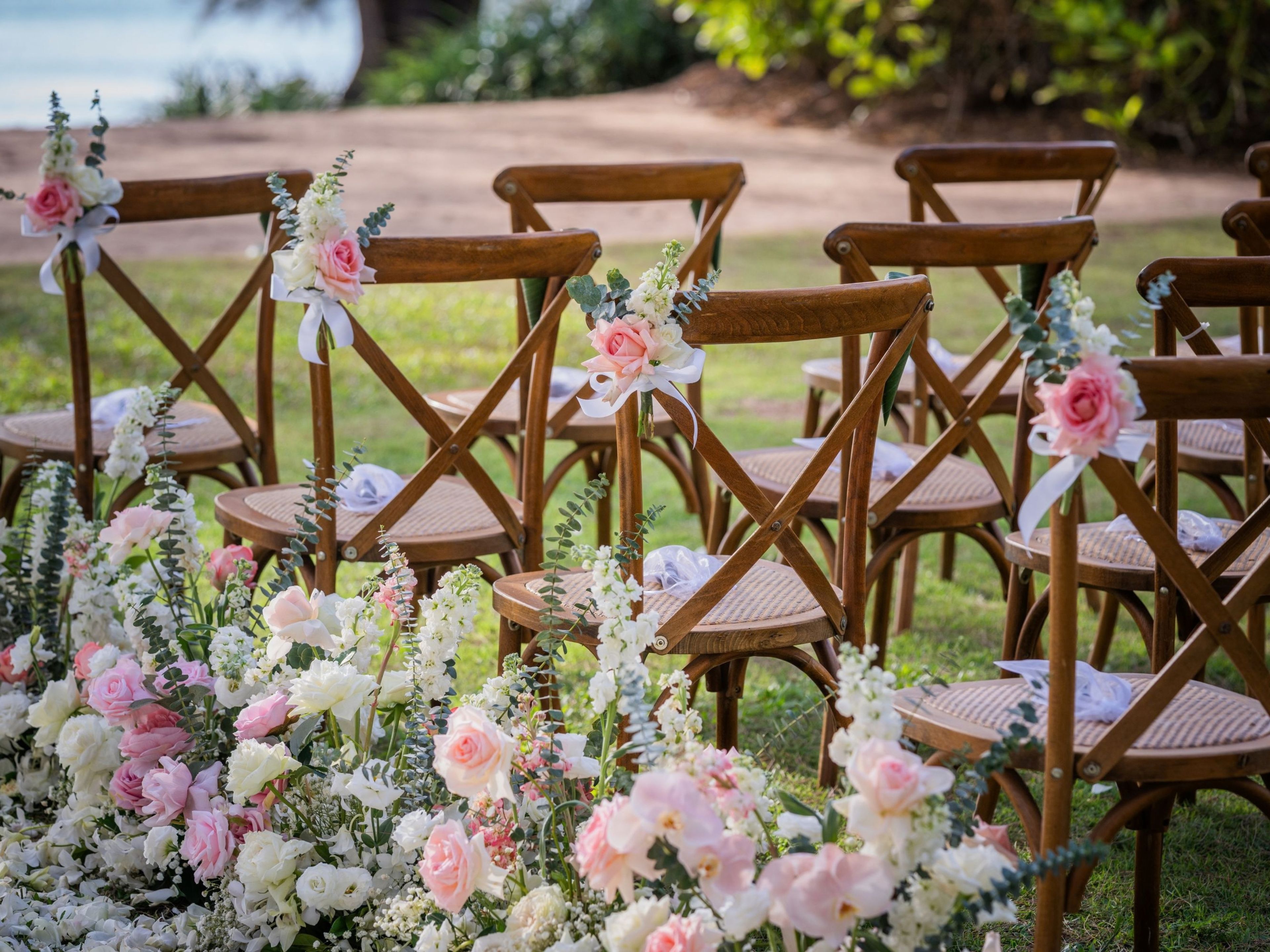 Outdoor wooden chairs arranged in rows, likely for an event, with floral decorations.