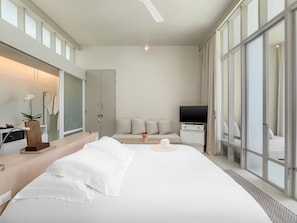 Ett modernt hotellrum med en stor säng, en TV, ett skrivbord och ett badrum.