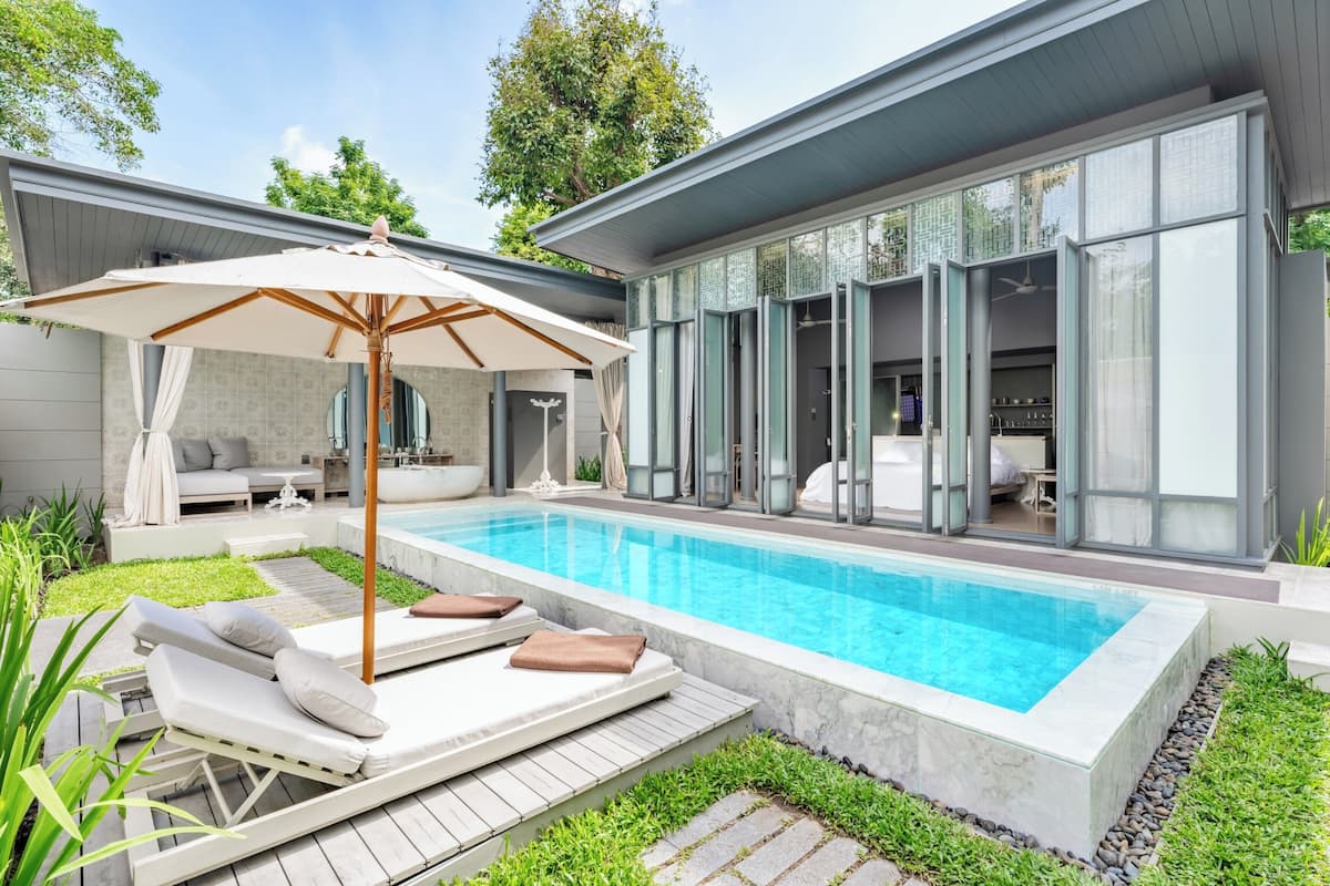 Ein moderner Poolbereich im Freien mit Liegestühlen und einer Pergola.