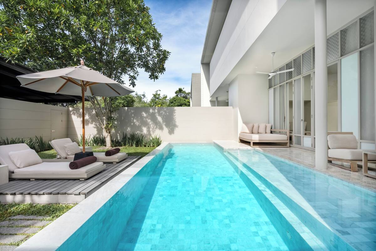 Ein moderner Poolbereich im Freien mit Liegestühlen und Deckenventilator.
