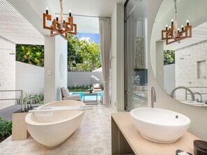 Un baño moderno con un lavabo de diseño, una bañera independiente y una zona de ducha con mampara de vidrio.