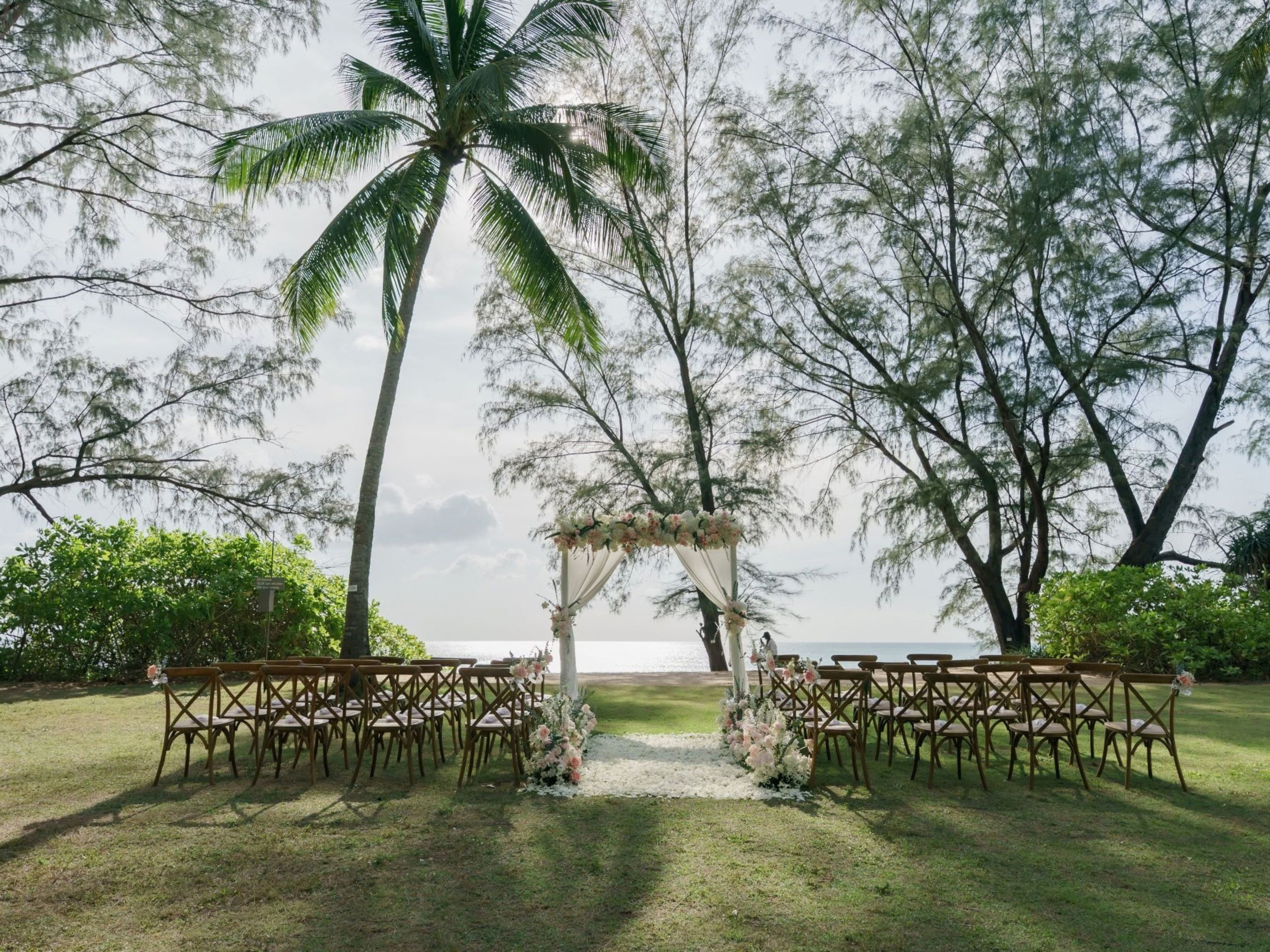 Decoración de boda al aire libre con un arco floral y sillas dispuestas para los invitados.