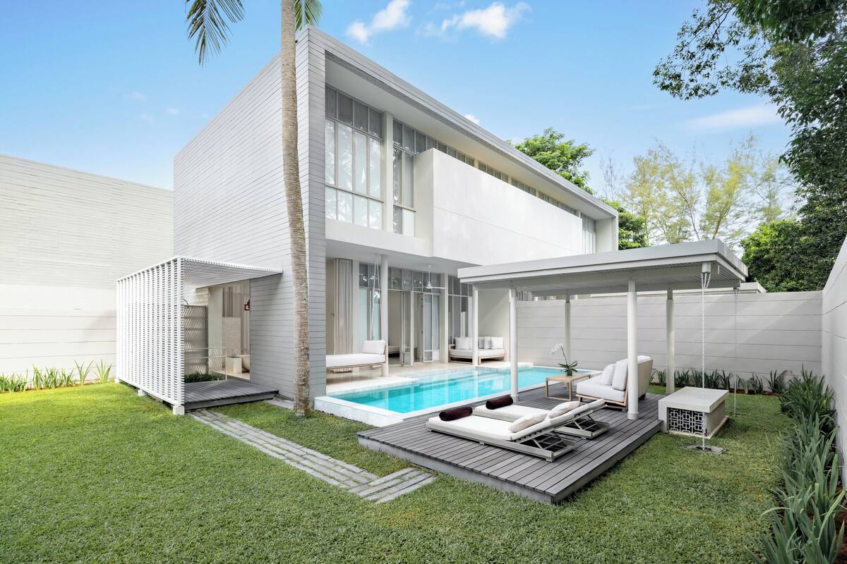 Ein modernes Haus mit Schwimmbad, Sitzgelegenheiten im Freien und einer überdachten Terrasse.