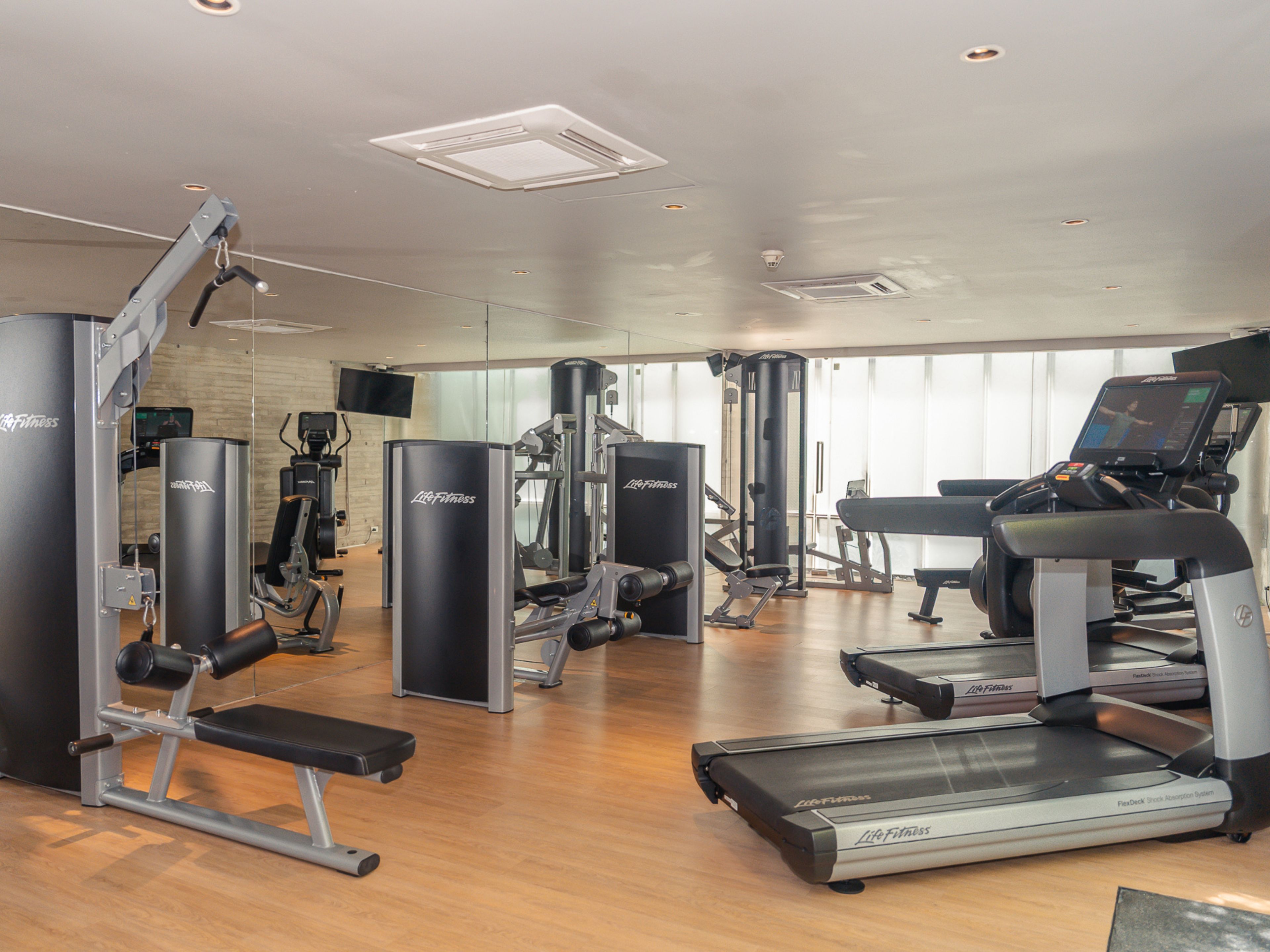 Un gimnasio con diversos equipos de ejercicio, incluyendo cintas de correr y máquinas de pesas.