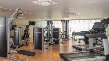 Un gimnasio con diversos equipos de ejercicio, incluyendo cintas de correr y máquinas de pesas.