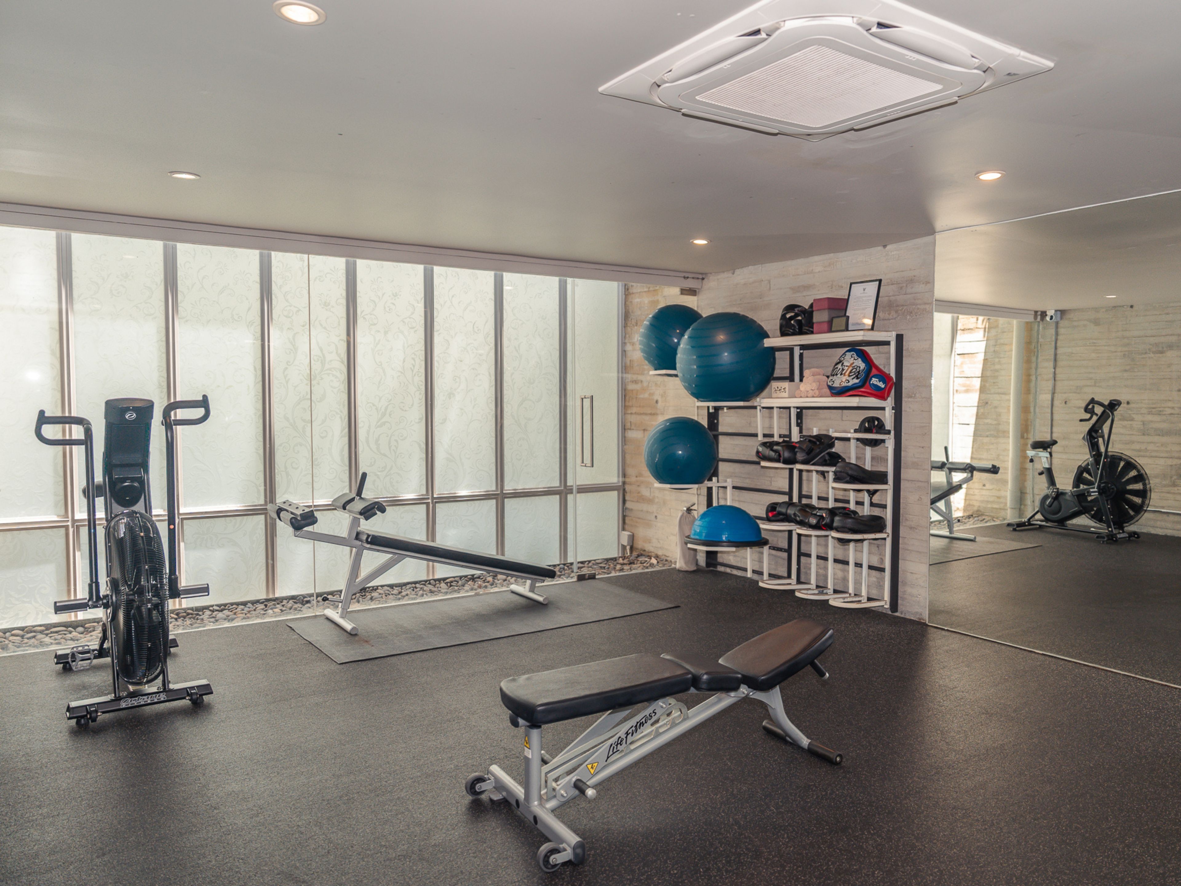 Ein Fitnessraum mit Trainingsgeräten, einer Sitzbank und einer Wand mit Regalen, die Dinge beherbergen.