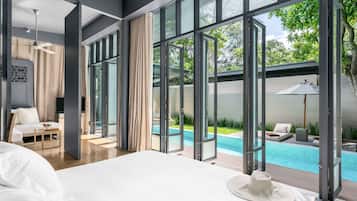 Habitación de hotel moderna con una cama grande, vista a una piscina al aire libre y un balcón con vista al verdor.