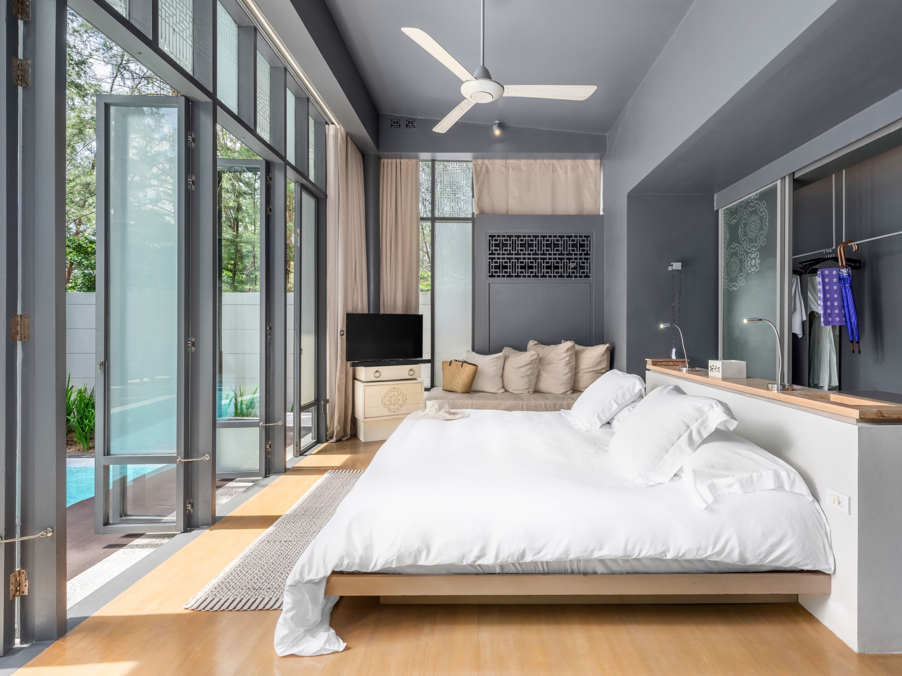 A modern bedroom with a large bed, a television, and a view of the outdoors.