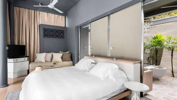 Un dormitorio moderno con una cama grande, televisor, ventilador de techo y vistas al exterior.