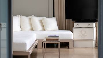 Habitación de hotel moderna con cama, televisor en un mueble bajo, mesita de noche con libros y un panel decorativo en la pared.