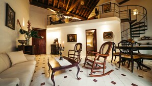 Un vaste salon doté d’un haut plafond, un coin repas avec une table et des chaises en bois, et un escalier menant à l’étage supérieur.
