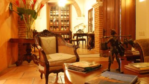 Une bibliothèque chaleureuse avec des étagères à livres, une chaise en bois et une statue.