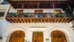 Un bâtiment doté d’un balcon en bois, de deux grandes portes en bois et de plantes en pot.