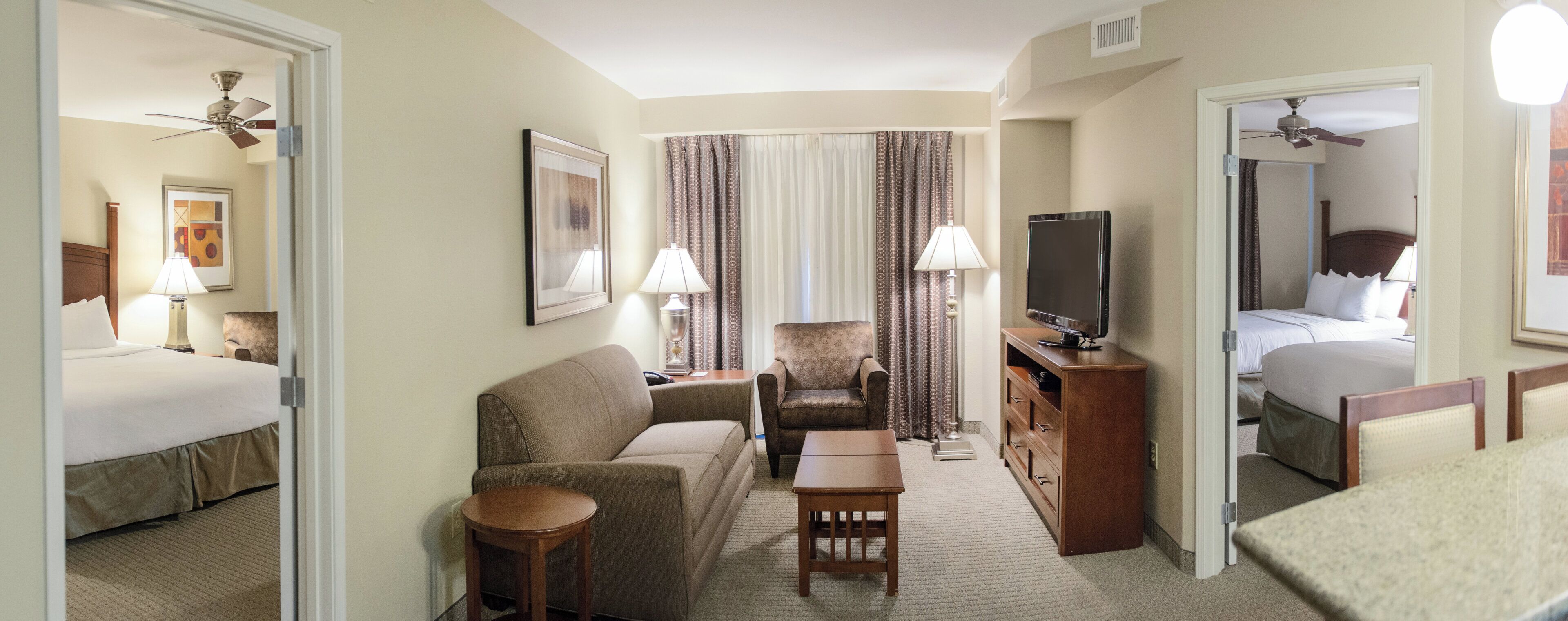 A hotel room with a bed, a sofa, a chair, a TV, and a desk.