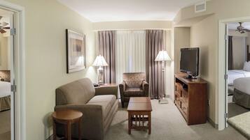 A hotel room with a bed, a sofa, a chair, a TV, and a desk.