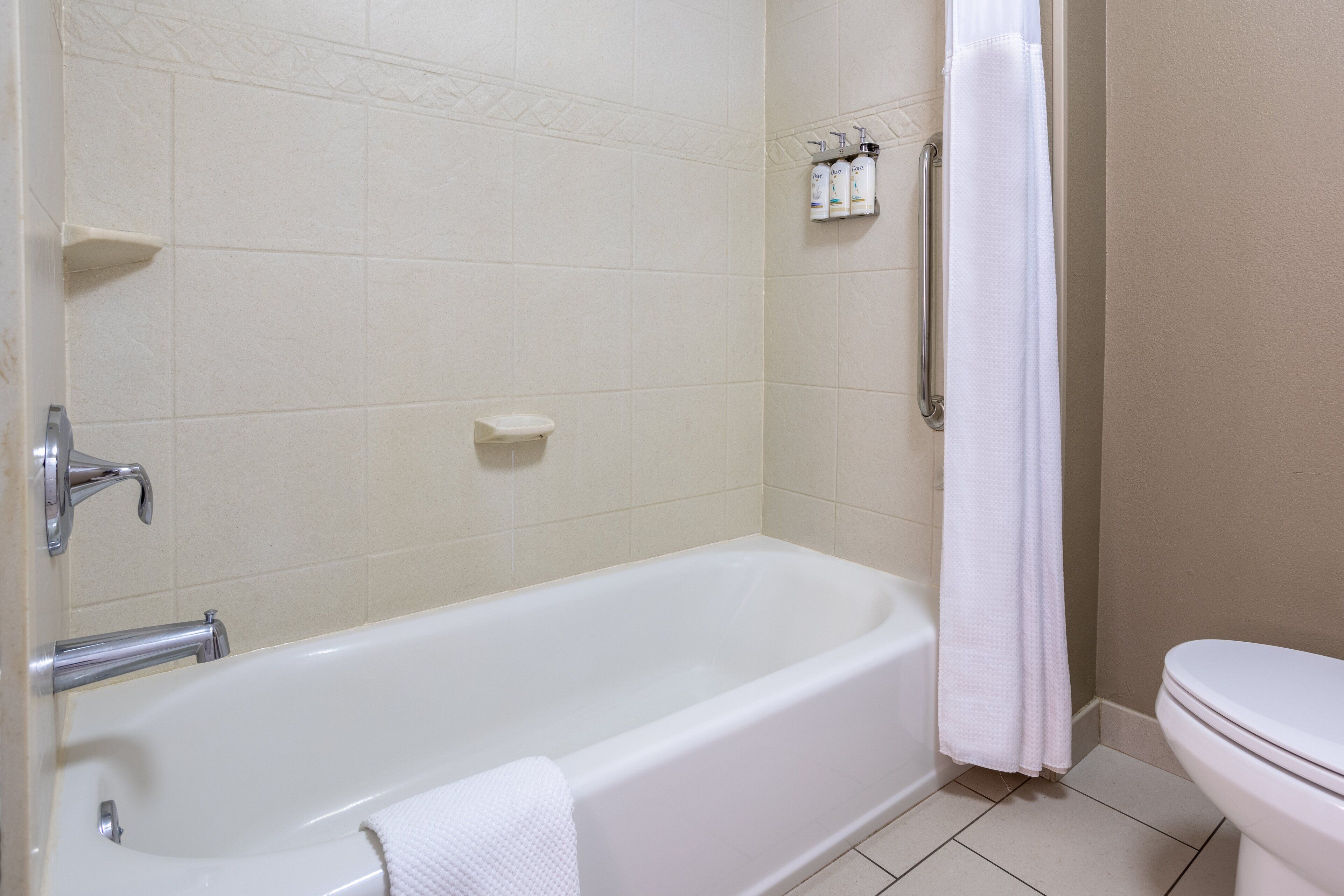 A bathroom with a bathtub, toilet, and a shower curtain.