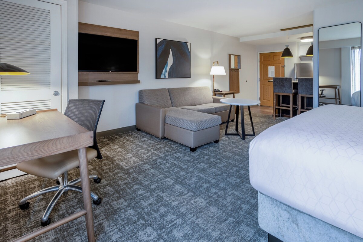 Een hotelkamer met een bed, een bank, een bureau, een stoel, een klein tafeltje en een televisie.