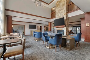 A spacious lounge area with multiple seating options, a fireplace, and a flat-screen TV mounted on the wall.