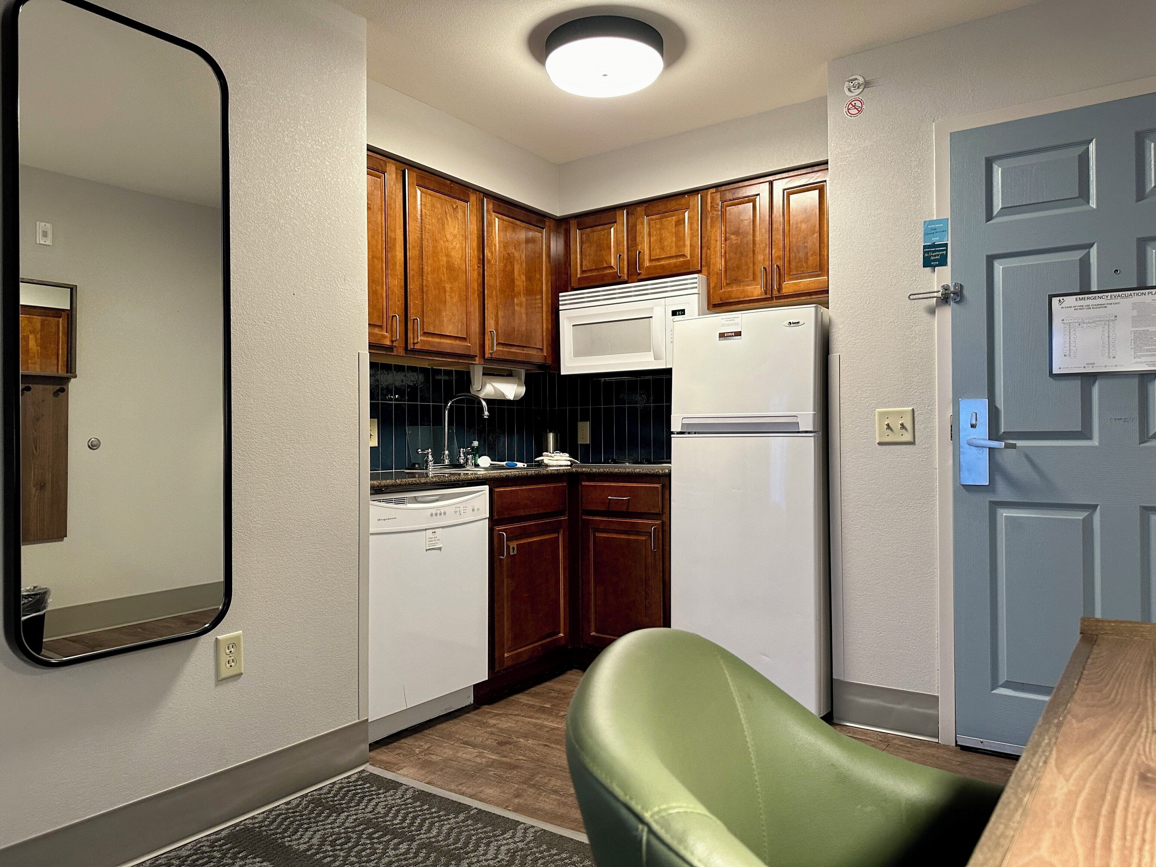 A compact kitchen with wooden cabinets, a white refrigerator, and a built-in dishwasher.