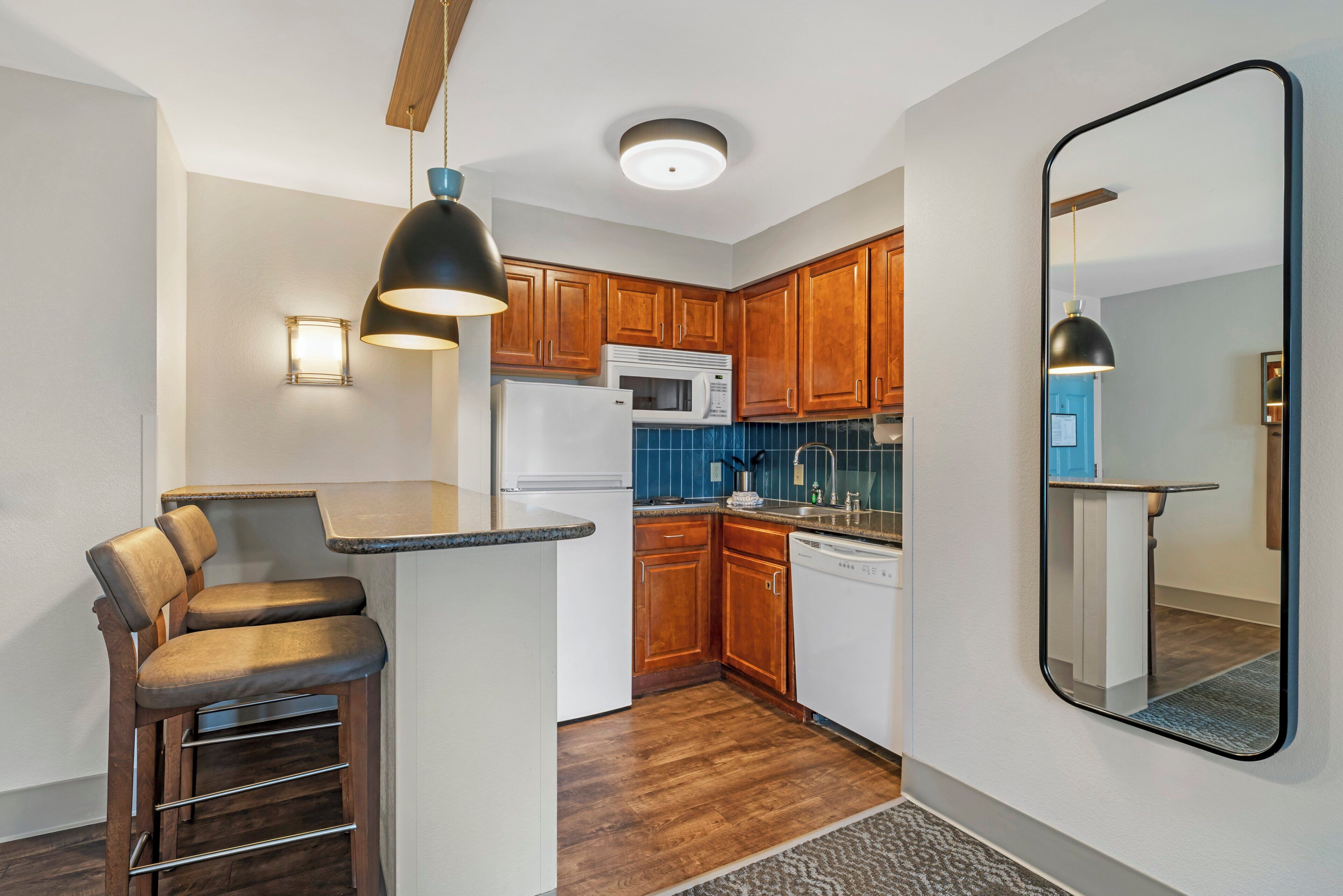 A compact kitchen with wooden cabinets, a built-in microwave, and a refrigerator.