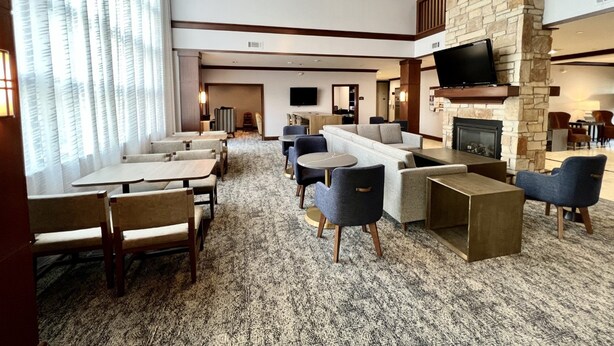 A hotel lobby with a fireplace, seating area, and a TV mounted on the wall.