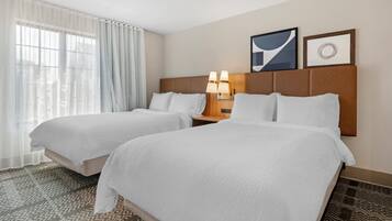 A hotel room with two beds, a nightstand with lamps, and two framed pictures on the wall.