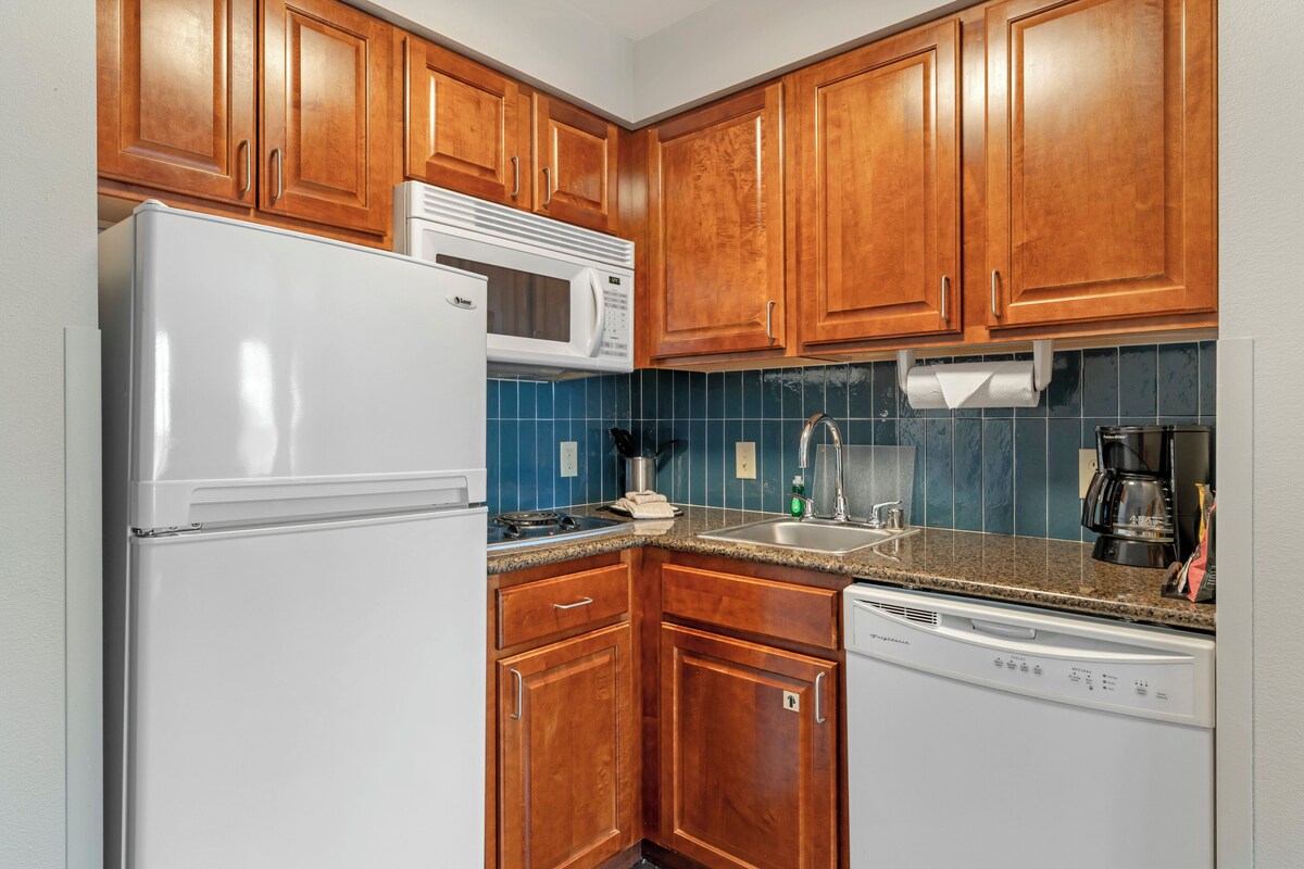 A kitchen with wooden cabinets, a white refrigerator, a microwave, a stove, a sink, and a dishwasher.