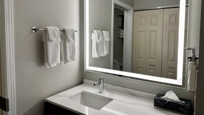 A bathroom with a white sink, a mirror, and two towels hanging on a towel rack.