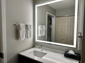 A bathroom with a white sink, a mirror, and two towels hanging on a towel rack. - Staybridge Suites Milwaukee West-Oconomowoc by IHG (Oconomowoc)