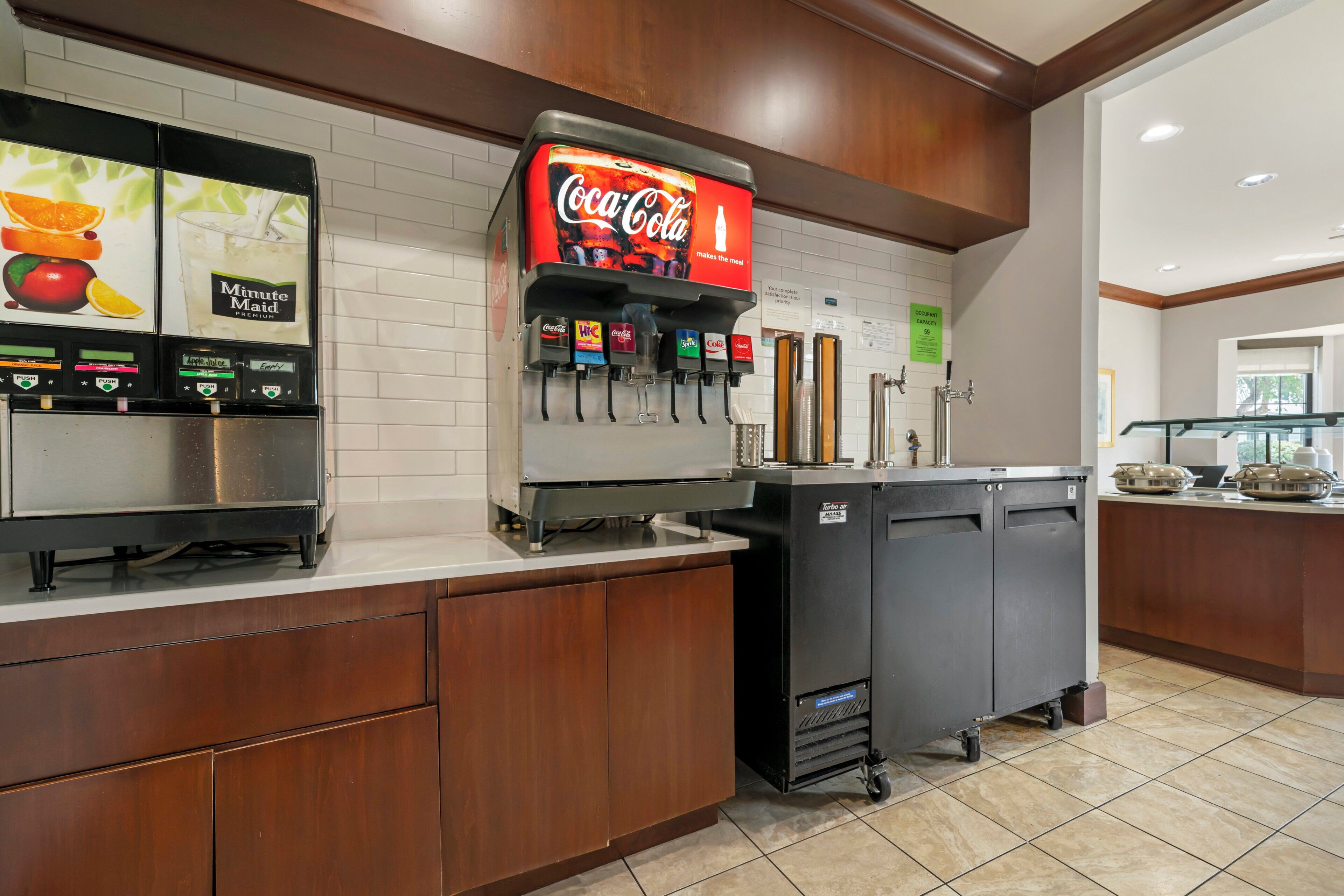 Una estación de autoservicio para bebidas con varias opciones, incluyendo Coca-Cola, HIC, Sprite y jugo de manzana.